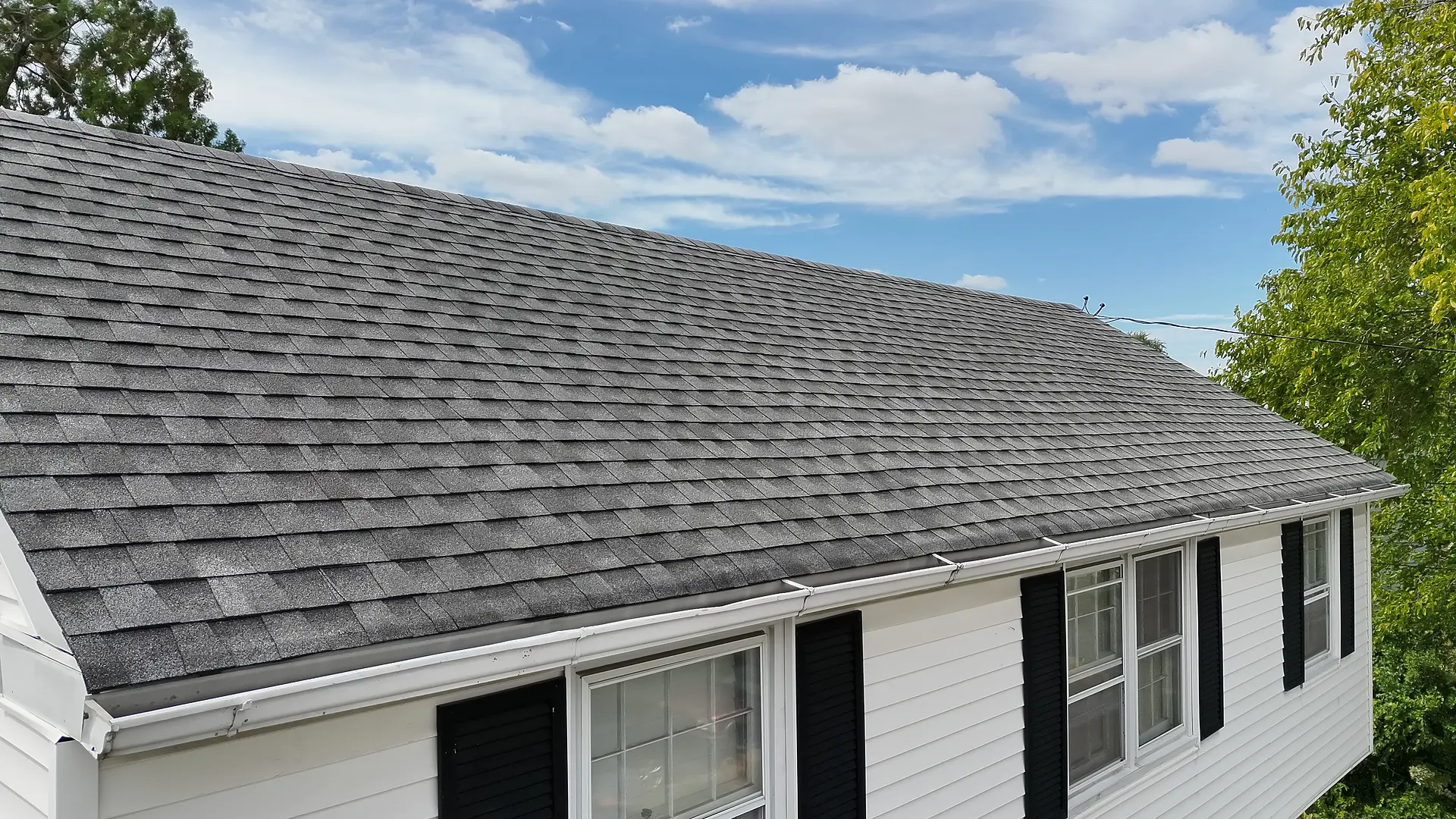Drone view of an asphalt shingle residential roof and front elevation.